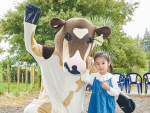 A young visitor befriends DairyNZ’s Rosie the Cowbassador at the Owl Farm open day.