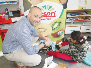 Zespri’s Michael Fox helps a Rata Primary School student try on her new pair of running shoes.