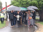 Matai Pacific Iwi Collective (MPIC) leaders carry the Ahuwhenua Trophy onto the marae in the rain.